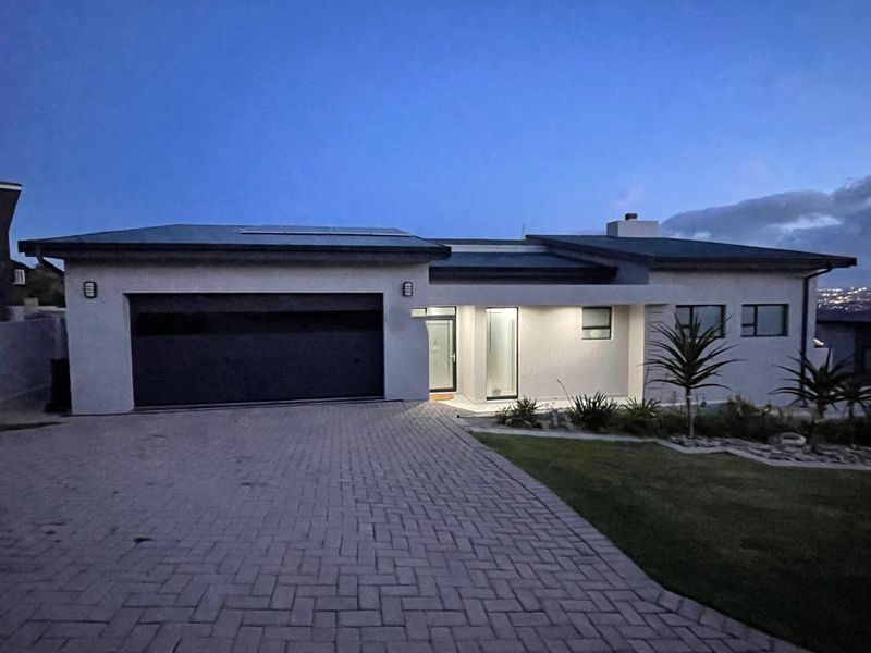 Modern single-story residential home featuring a paved driveway, double garage, and well-maintained front garden at twilight.