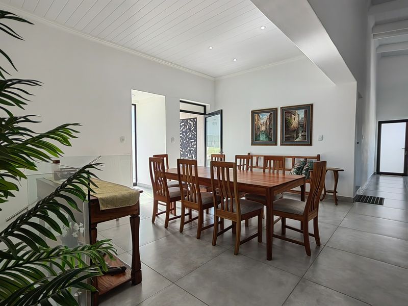 Spacious dining area featuring large format floor tiles, a white tongue and groove ceiling with recessed lighting, and direct access to the exterior.
