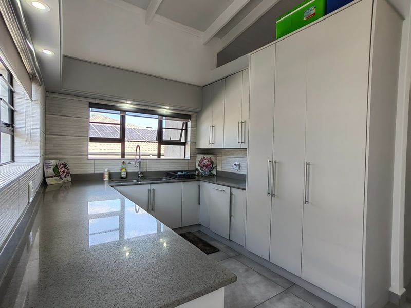 Modern kitchen featuring sleek stone countertops, ample built-in cabinetry, and a stainless steel sink, offering a clean and functional workspace.