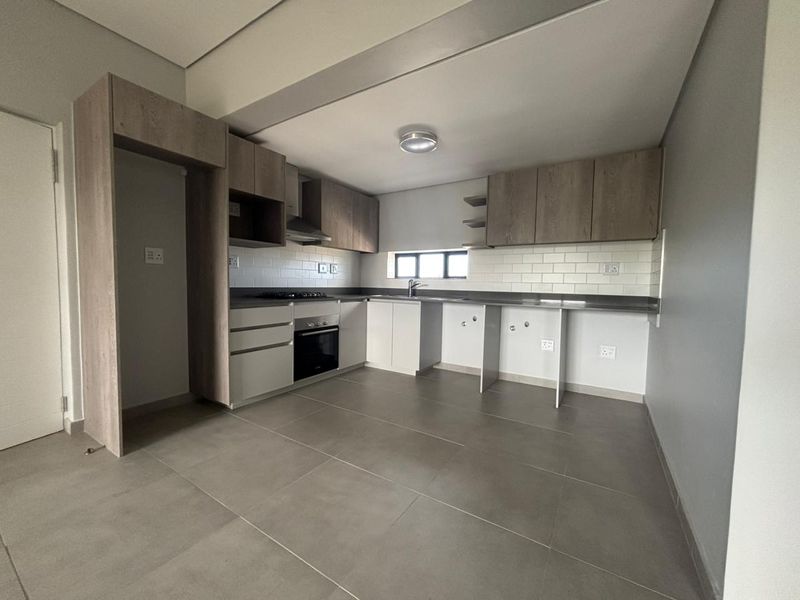 Modern kitchen featuring neutral cabinetry, subway tile backsplash, built-in oven and hob, and tiled flooring in an open-plan layout.