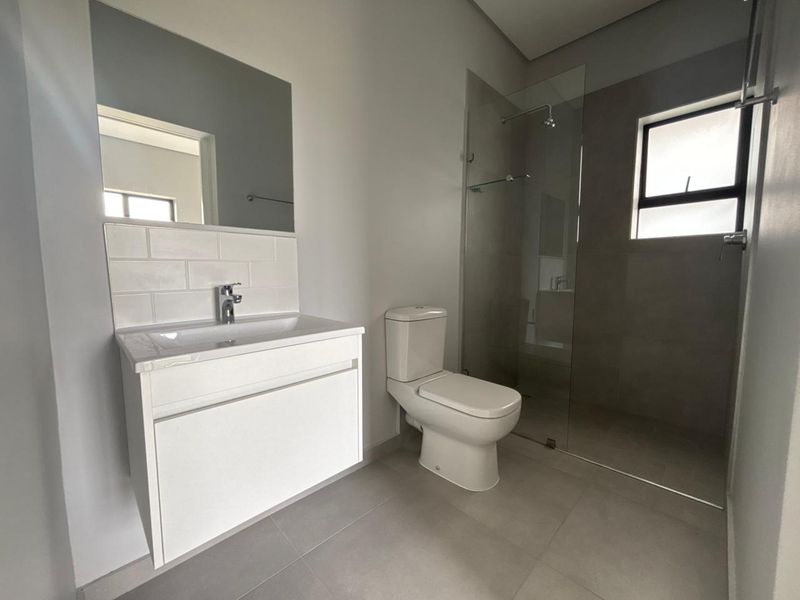 Modern bathroom featuring a floating vanity, glass-enclosed shower, and neutral tile finishes in excellent condition.