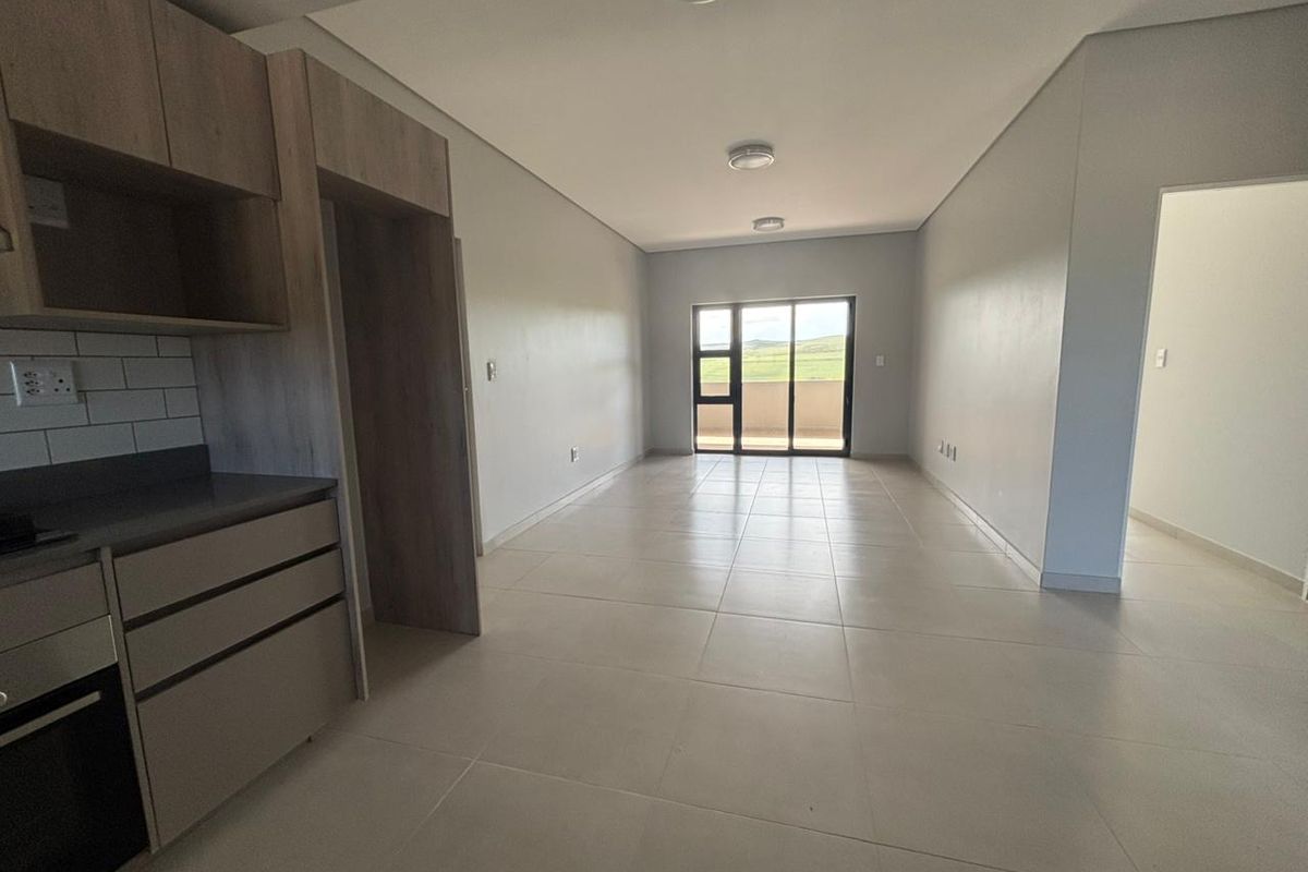 An open-plan living and kitchen area featuring modern cabinetry, tiled flooring, and a sliding glass door leading to an outdoor space.