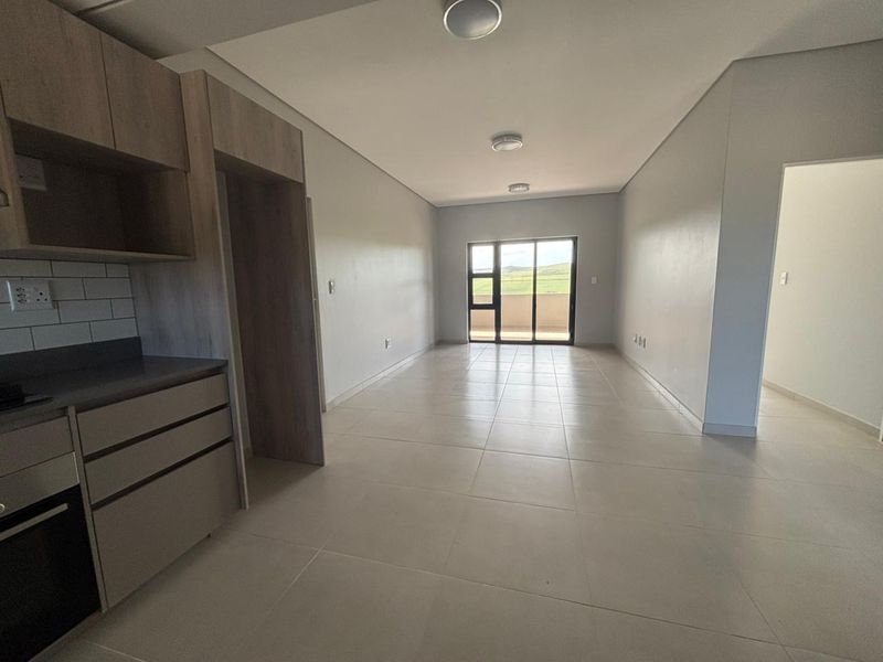 An open-plan living and kitchen area featuring modern cabinetry, tiled flooring, and a sliding glass door leading to an outdoor space.