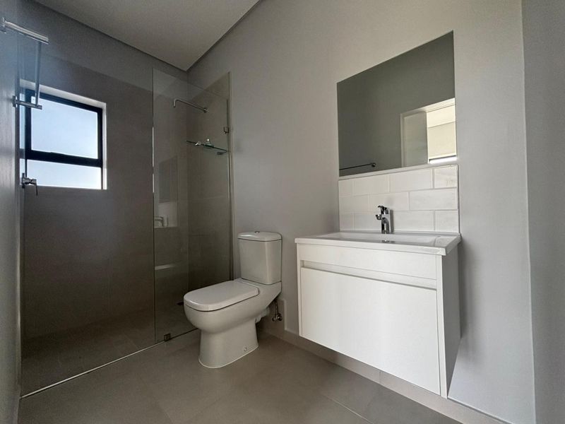 Modern bathroom featuring a wall-mounted vanity, subway tile splashback, and a spacious walk-in shower with a glass screen.