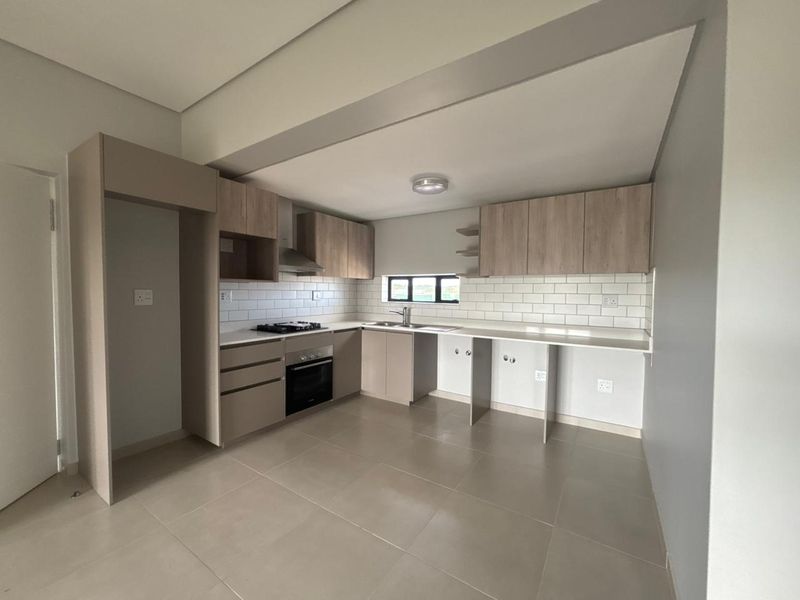 Modern, clean-lined kitchen featuring neutral cabinetry, subway tile backsplash, built-in oven and hob, and ample counter space in an open-plan layout.