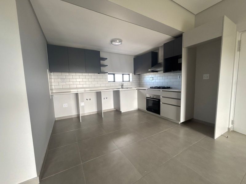 Modern kitchen featuring sleek grey cabinetry, subway tile backsplash, integrated oven, gas hob, and tiled flooring in an open-plan layout.