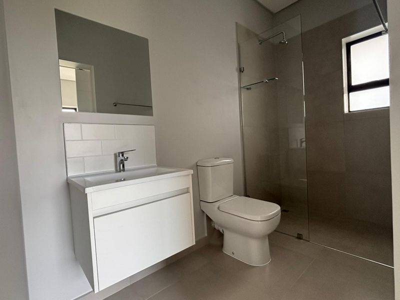 Modern bathroom featuring a wall-mounted vanity, subway tile splashback, close-coupled toilet, and a spacious walk-in shower with a glass screen.