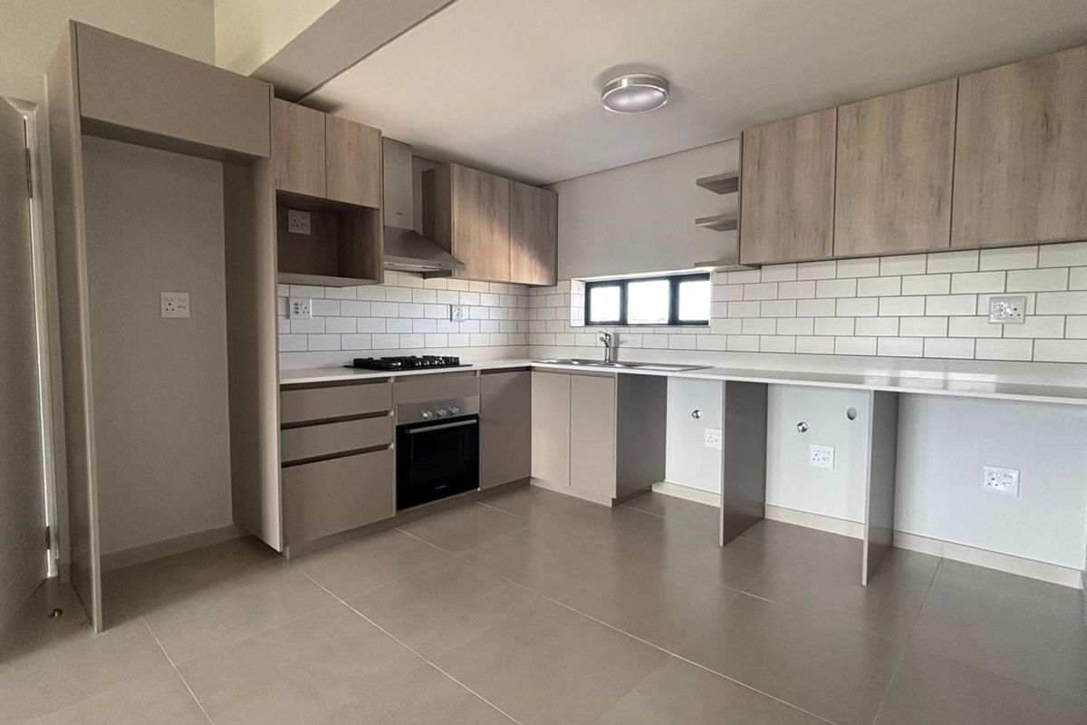 Modern kitchen featuring light wood-tone cabinetry, stone countertops, subway tile backsplash, and integrated appliances including a gas hob and oven.
