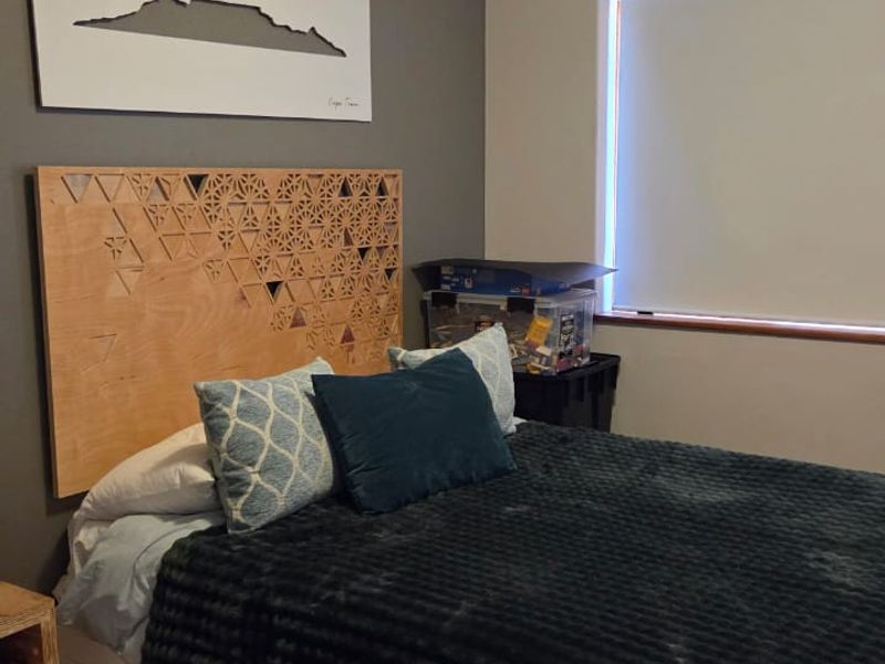 A well-maintained bedroom featuring laminate flooring, a neutral color palette, and a roller blind for privacy.