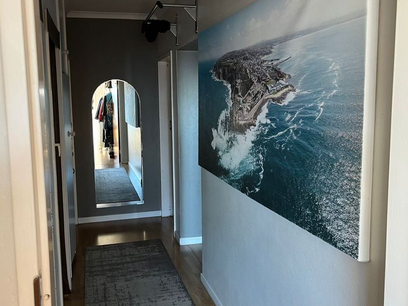 A well-maintained hallway featuring laminate flooring and a distinctive arched doorway leading to adjacent living spaces.