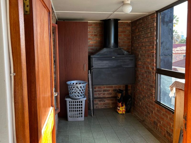 Enclosed balcony area featuring a built-in braai, exposed brick walls, and tiled flooring, offering a functional space for outdoor cooking and relaxation.