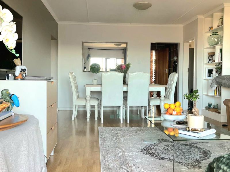 An open-plan living and dining area featuring laminate flooring and a built-in shelving unit, creating a functional and connected living space.