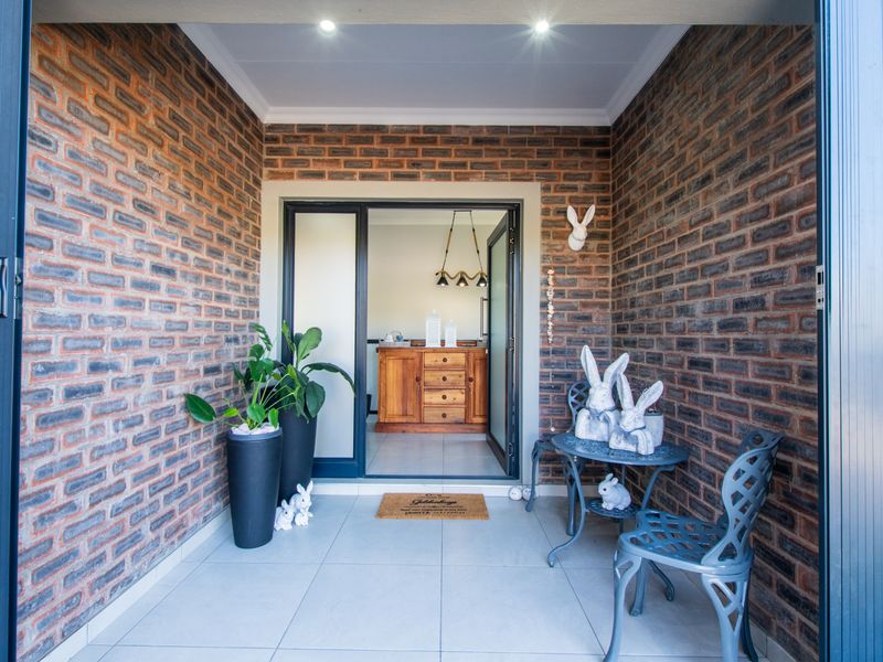 A covered patio area featuring exposed brick walls, tiled flooring, and recessed downlights, providing a seamless transition to the interior living space.