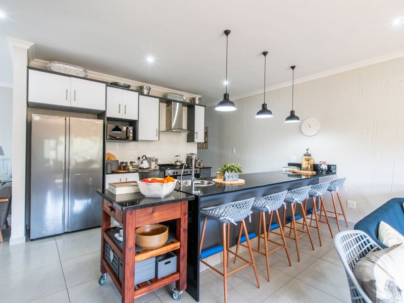 Modern open-plan kitchen featuring a large island with granite countertops, sleek cabinetry, and contemporary pendant lighting, seamlessly integrated with the living area.