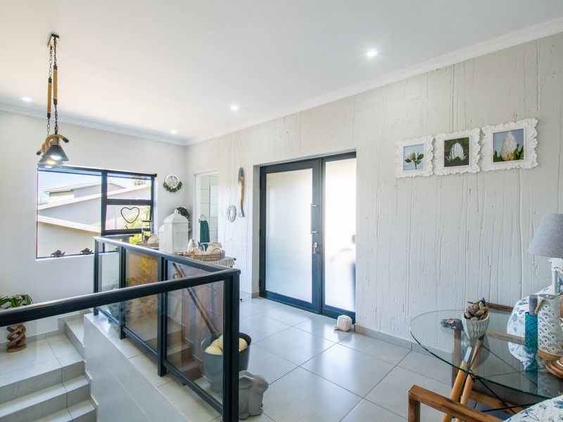 Bright and modern entrance hall featuring a textured feature wall, tiled flooring, and a contemporary glass balustrade overlooking the staircase.