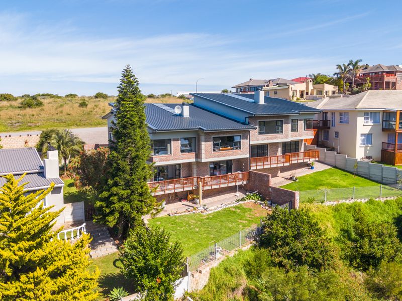 Aerial view of a multi-story duet property featuring a metal roof, brick exterior, and spacious wooden decks overlooking a private garden.