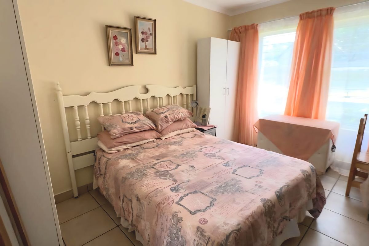A bedroom featuring tiled flooring and a built-in wardrobe, offering a functional space with natural light.