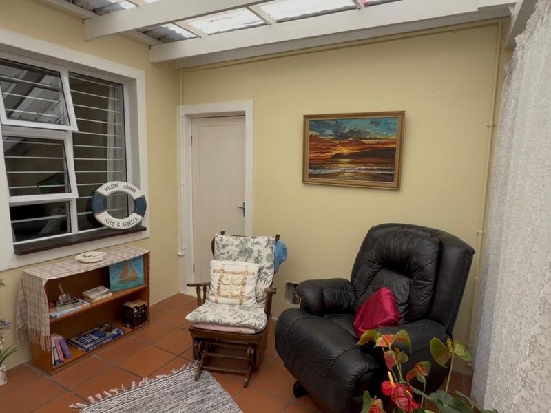 A sunroom or enclosed patio featuring terracotta floor tiles, a translucent roof, and a louvre window, providing a bright and functional transition space.