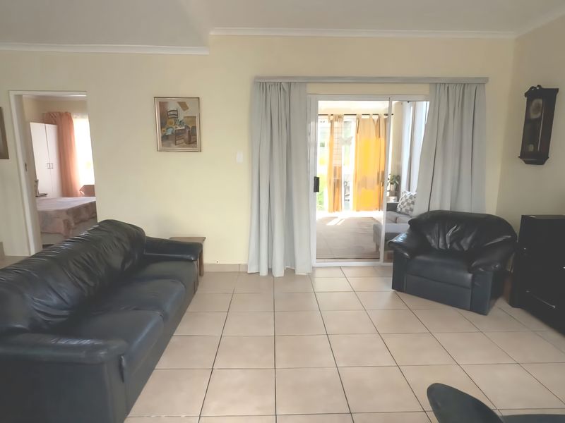 A living room featuring tiled flooring and a sliding glass door providing access to an enclosed patio area.