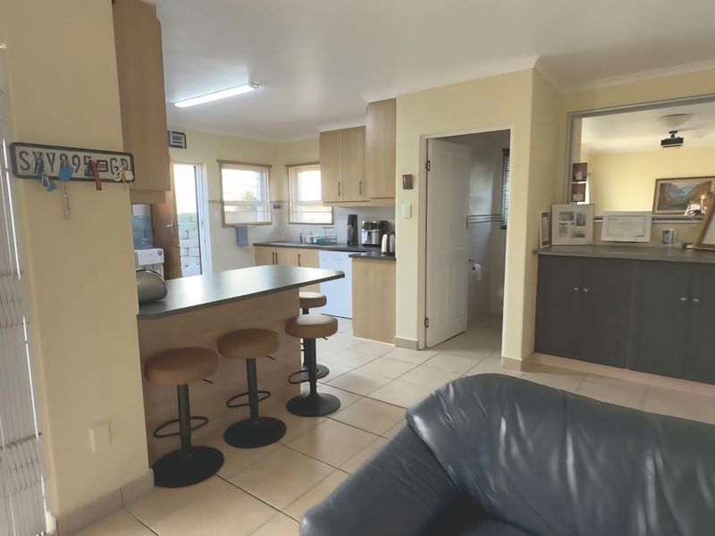 Open-plan living area featuring a kitchen with island, tiled flooring, and built-in cabinetry, providing a functional and connected space for daily living.