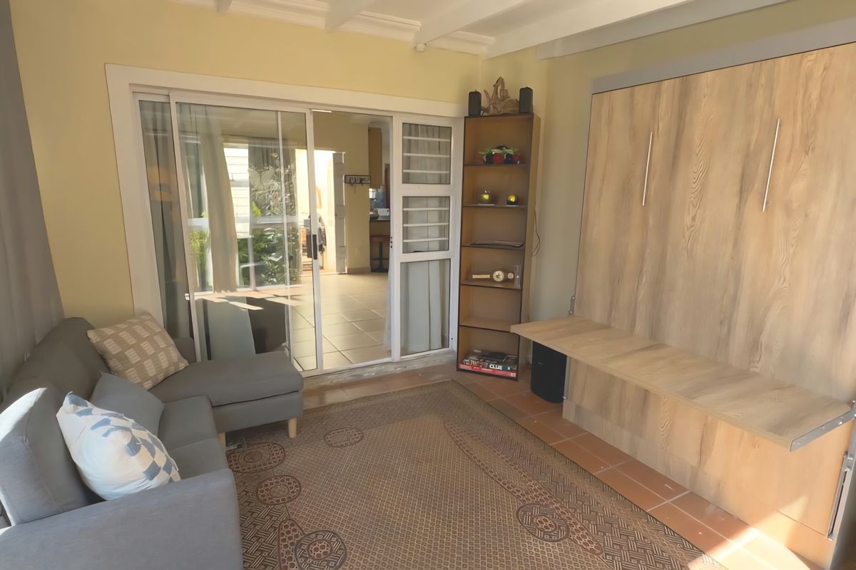 A living room featuring a built-in wall unit, tiled flooring, and sliding glass doors that provide access to an outdoor patio area.