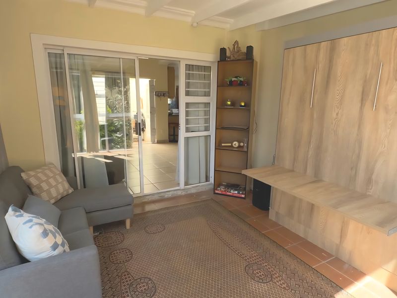 A living room featuring a built-in wall unit, tiled flooring, and sliding glass doors that provide access to an outdoor patio area.