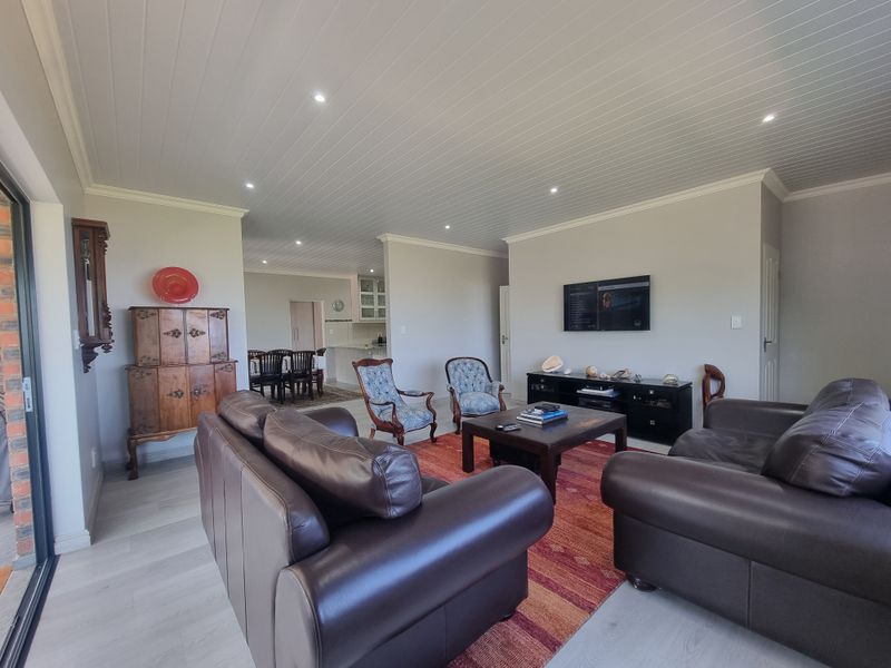 Spacious open-plan living area featuring light laminate flooring, a tongue and groove ceiling with recessed lighting, and seamless flow to the kitchen and dining space.