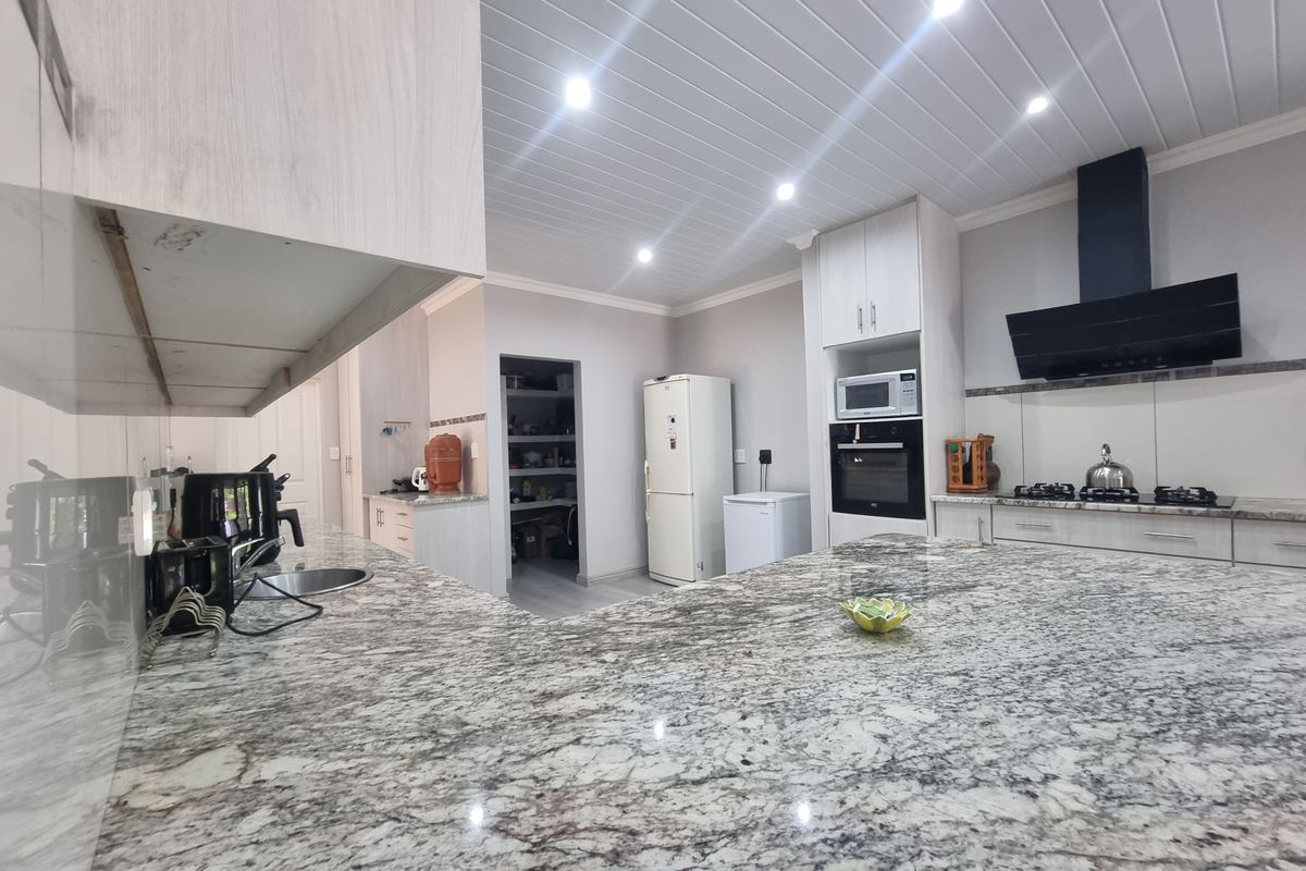 Modern kitchen featuring granite countertops, built-in oven, gas hob, extractor fan, and a convenient walk-in pantry with recessed lighting.