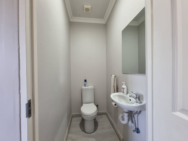 A clean and functional guest cloakroom featuring a wall-mounted basin, modern toilet, and neutral finishes.