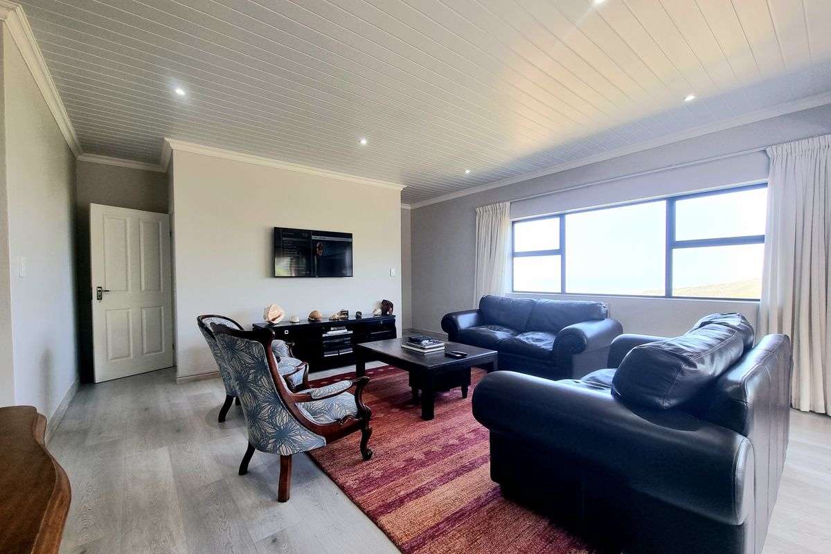 Spacious living room featuring modern laminate flooring, a tongue and groove ceiling with recessed lighting, and a large window providing natural light.
