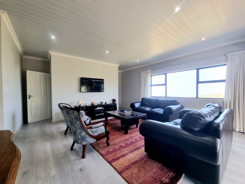 Spacious living room featuring modern laminate flooring, a tongue and groove ceiling with recessed lighting, and a large window providing natural light.