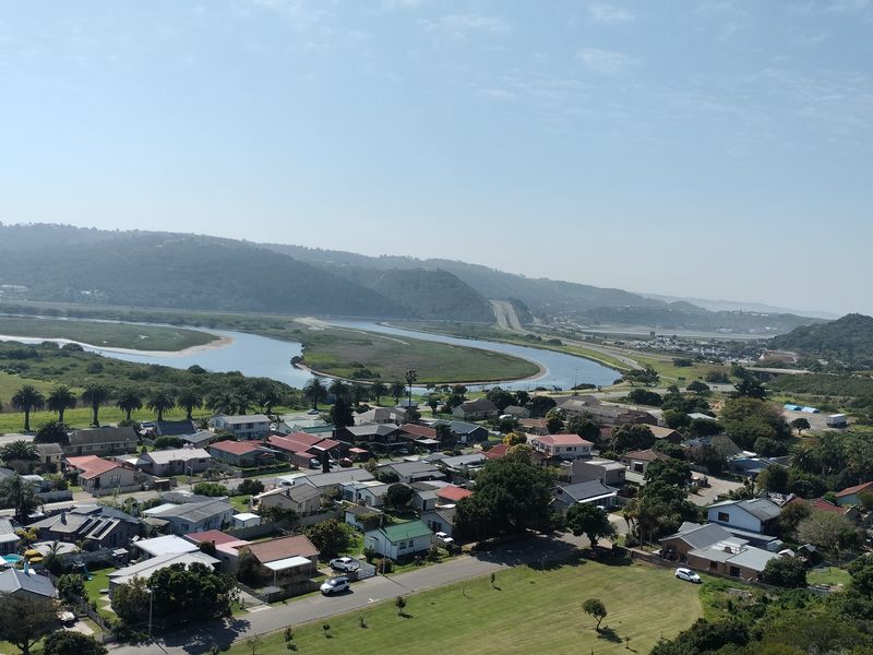 An elevated aerial view of a residential neighborhood situated near a river and coastal landscape.