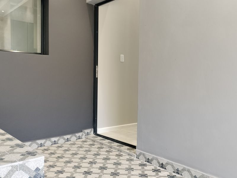 A clean, modern outdoor patio area featuring decorative patterned floor tiles and a neutral color palette, providing a seamless transition to the interior space.
