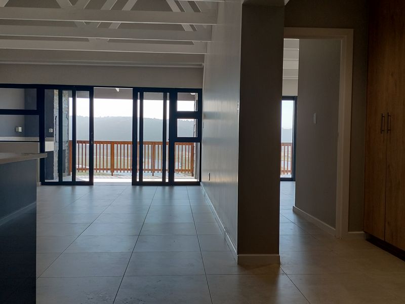 Spacious open-plan living area featuring exposed beam ceilings, large sliding glass doors leading to a balcony, and ample built-in storage cabinetry.