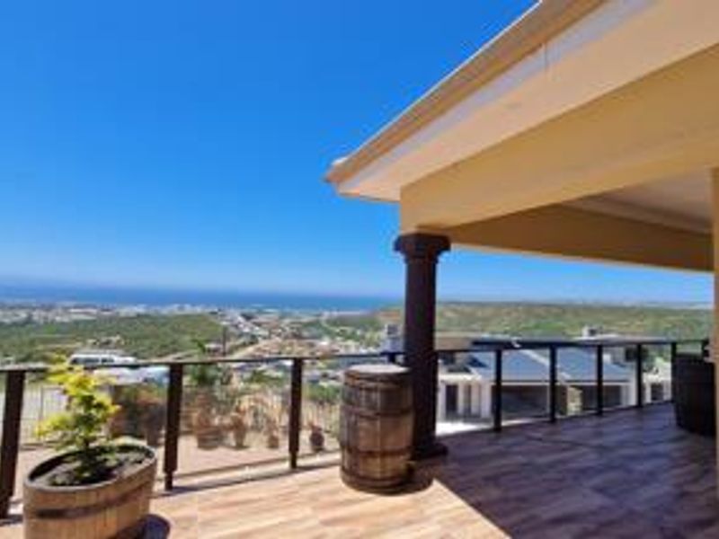 Spacious covered balcony featuring tiled flooring, a modern glass balustrade, and expansive panoramic coastal views.