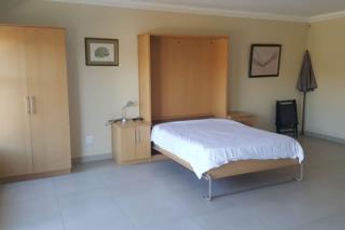 A functional bedroom featuring tiled flooring, cove cornicing, and a built-in murphy bed unit with integrated storage cabinetry.