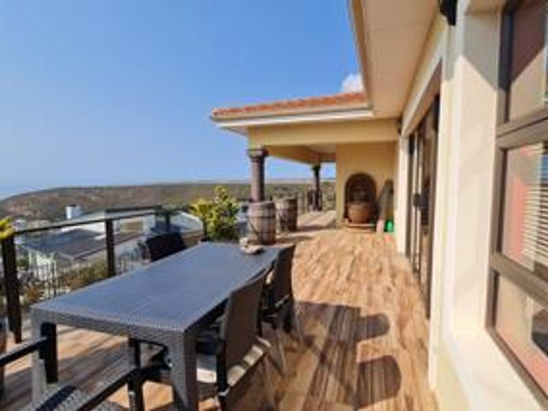 Spacious covered patio featuring wood-look tiled flooring, a glass balustrade, and expansive views, providing an ideal outdoor entertainment area.