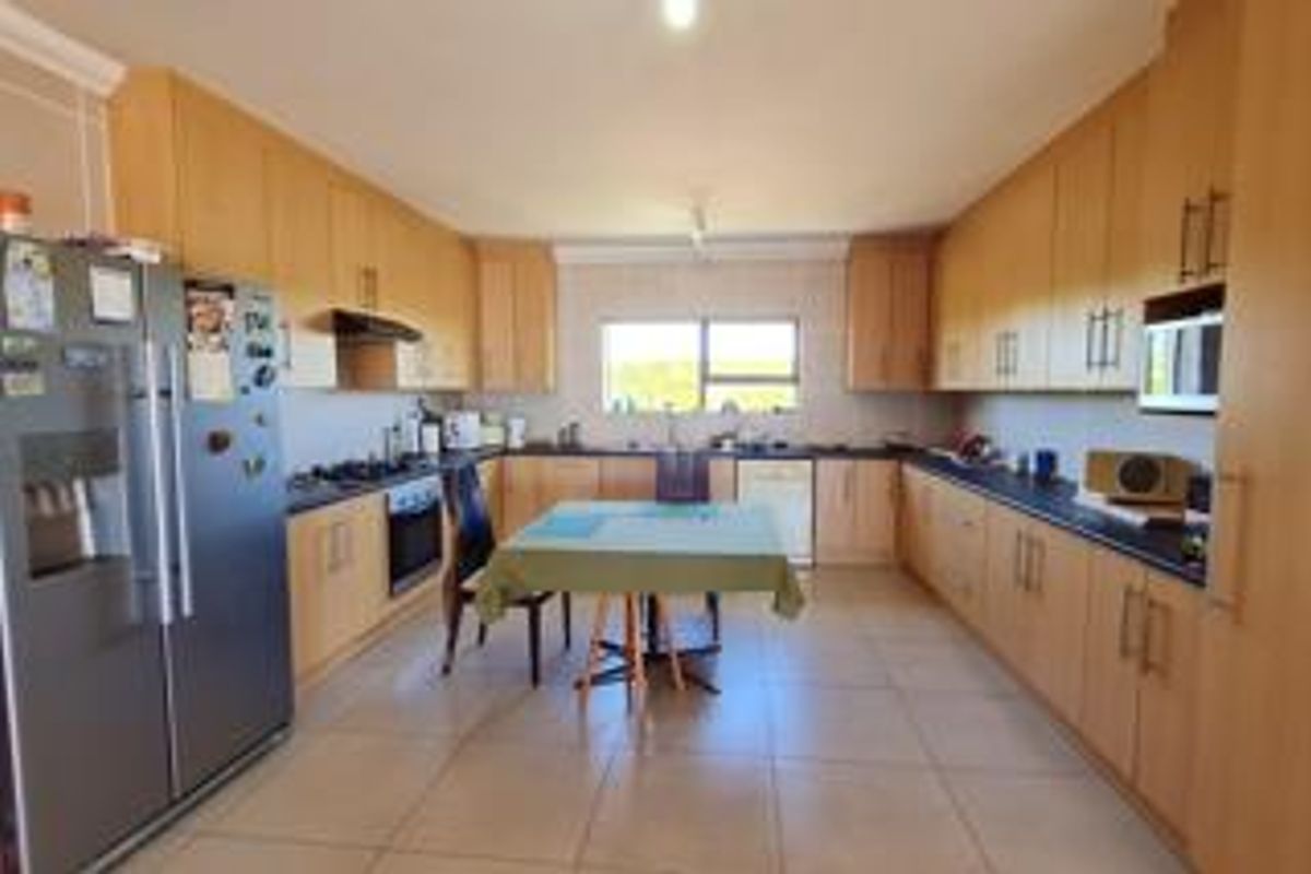 Spacious kitchen featuring extensive light wood cabinetry, dark countertops, built-in appliances, and tiled flooring, offering a functional layout with ample storage space.
