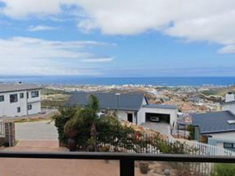 Elevated view overlooking the surrounding residential estate and distant coastline, captured from a balcony.
