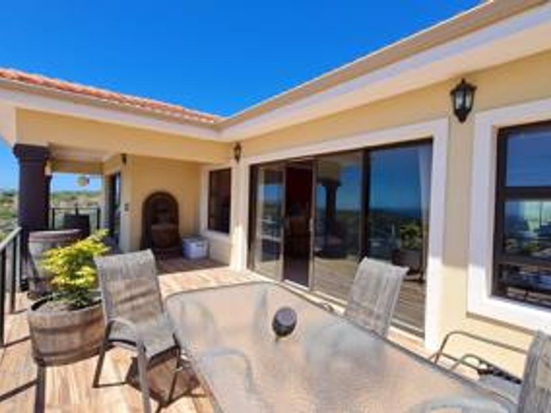 A covered patio area featuring sliding glass doors, tiled roof, and exterior lighting, offering a functional outdoor living space.