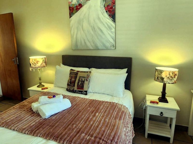 A well-maintained bedroom featuring neutral wall tones, tiled flooring, and a standard solid core door.