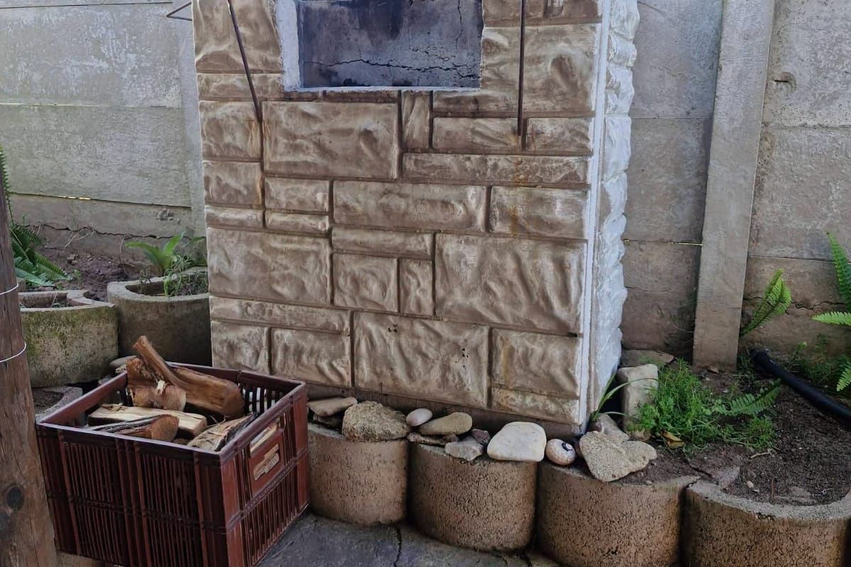 Outdoor area featuring a built-in stone-clad braai unit set against a precast concrete boundary wall with tiered concrete retaining blocks.