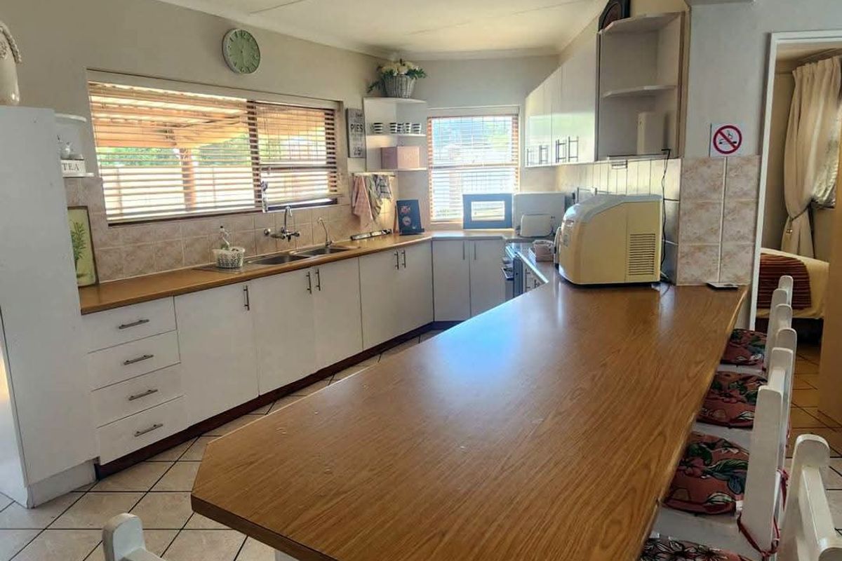 Functional kitchen featuring white cabinetry, laminate countertops, a breakfast bar, and tiled flooring, offering a practical layout for daily meal preparation.