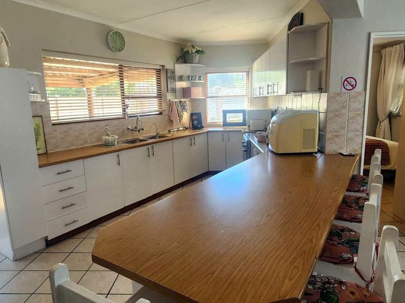 Functional kitchen featuring white cabinetry, laminate countertops, a breakfast bar, and tiled flooring, offering a practical layout for daily meal preparation.