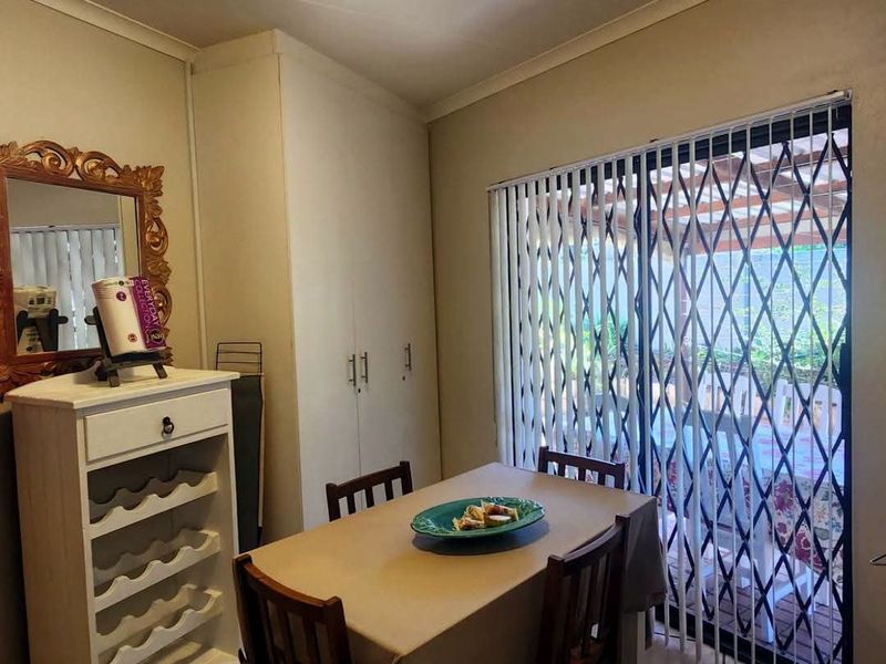 Dining area featuring tiled flooring, built-in storage cupboards, and a sliding glass door with security gate providing access to the outdoor patio.