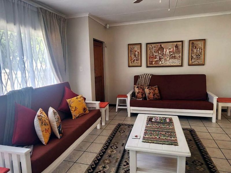 A living room featuring ceramic floor tiles, a ceiling fan, and a security gate over the window.