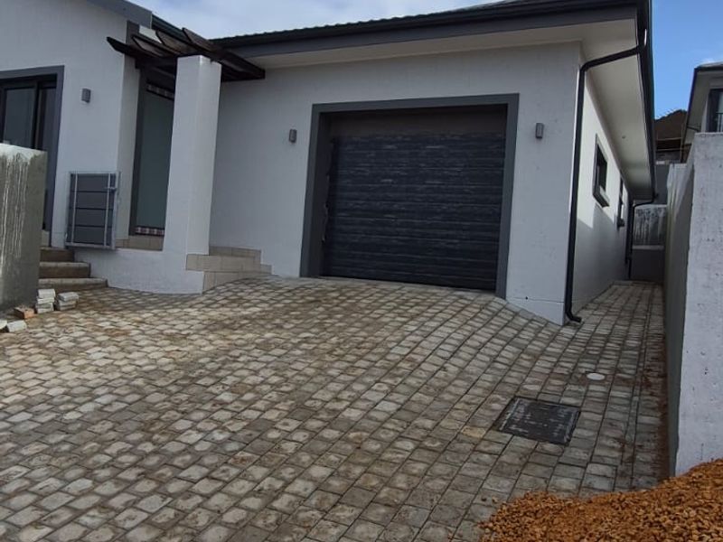 Front exterior view of the property featuring a paved driveway, modern garage door, and clean rendered facade.