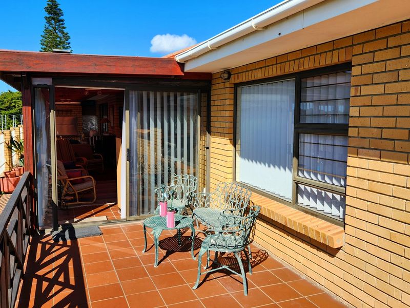 A covered outdoor patio area featuring tiled flooring, brick exterior walls, and a timber pergola, providing direct access to the interior living space.