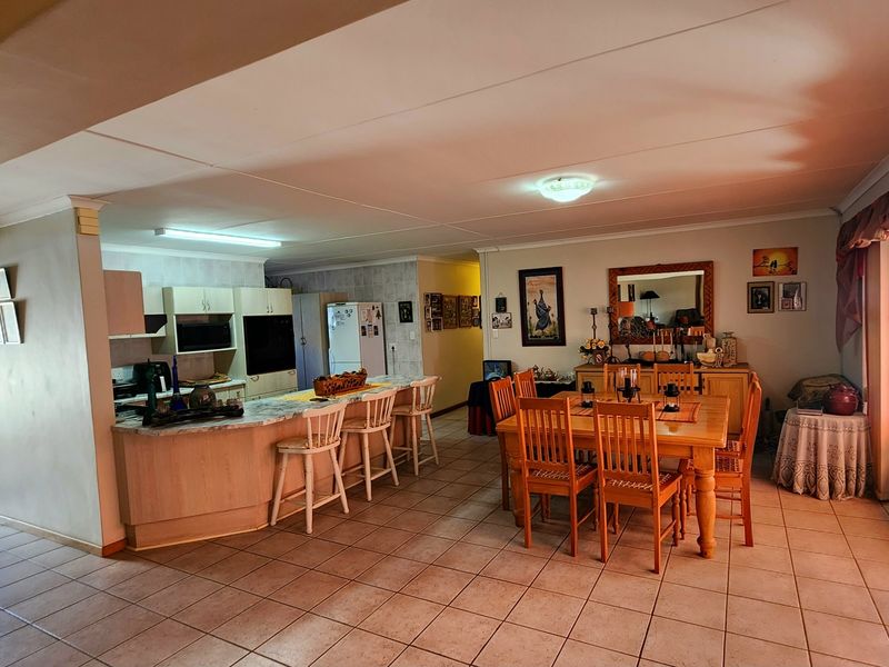 Open-plan living and dining area featuring a functional kitchen with built-in cabinetry, island seating, and tiled flooring throughout.