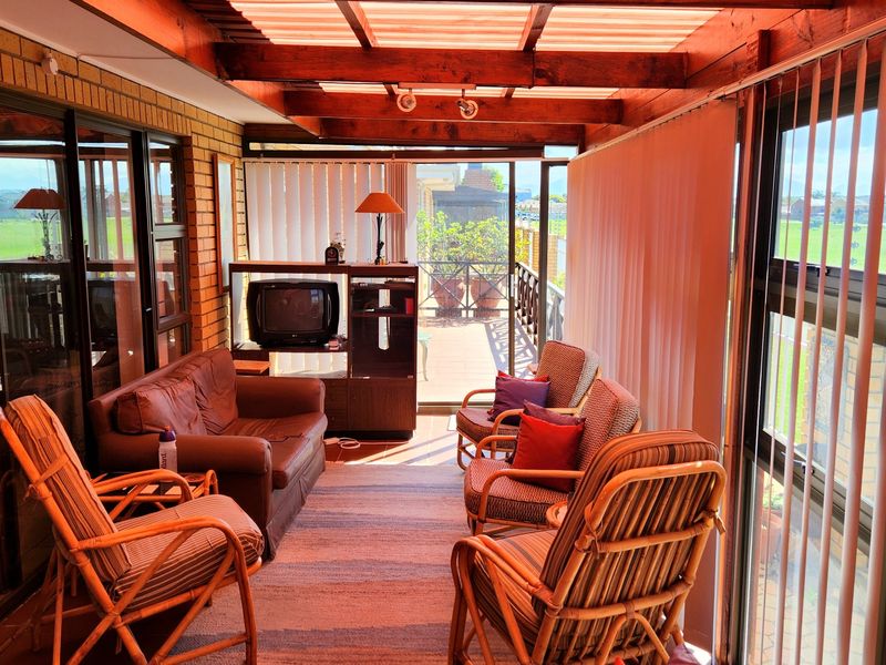 Enclosed patio area featuring a timber pergola roof, tiled flooring, and large sliding glass doors providing views of the surrounding grounds.